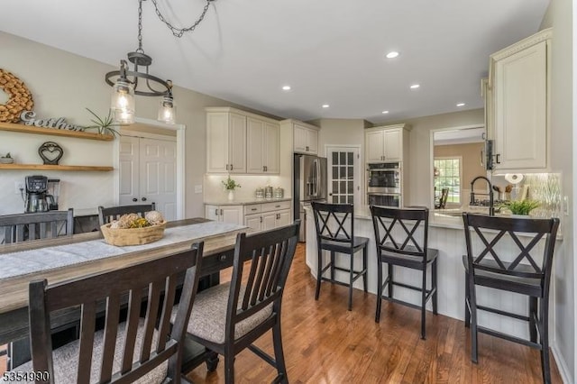 kitchen featuring a peninsula, appliances with stainless steel finishes, wood finished floors, and a sink