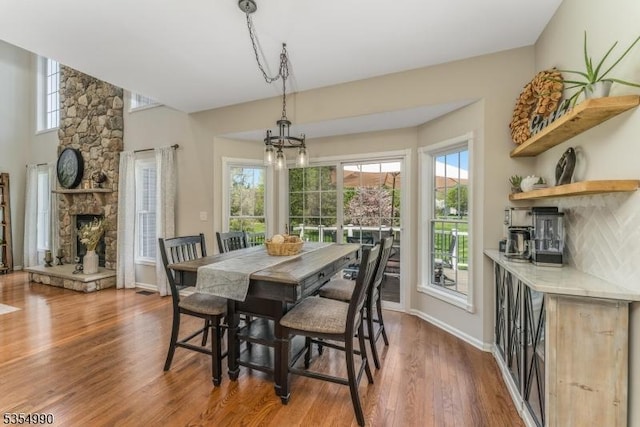 dining area with baseboards, wood finished floors, a fireplace, and a healthy amount of sunlight