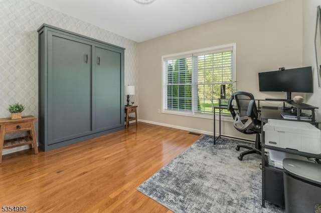 office area with baseboards, wallpapered walls, and light wood-style floors