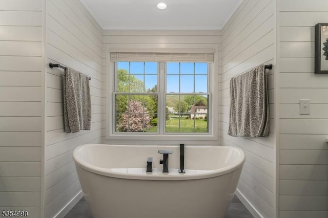 full bathroom featuring wooden walls and a freestanding tub