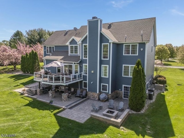 rear view of property with a fire pit, a patio, a wooden deck, a chimney, and a lawn