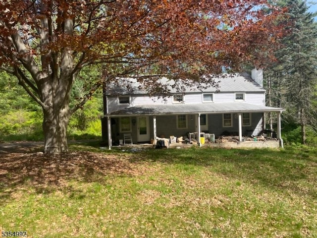 rear view of property featuring a lawn and a chimney