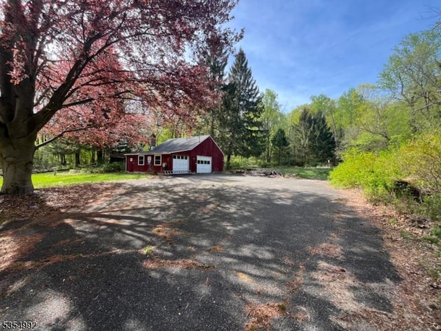 exterior space featuring a wooded view and aphalt driveway