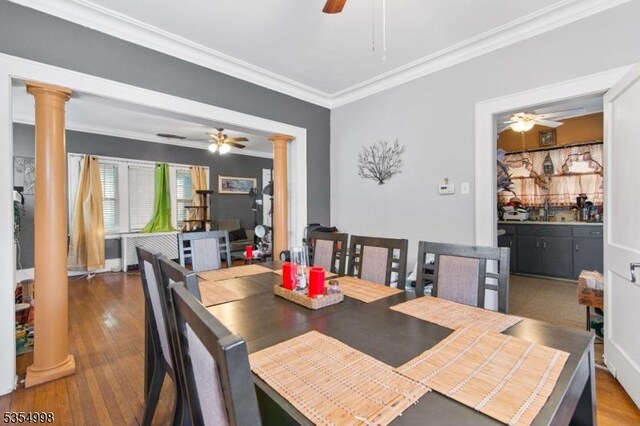 dining room with ornate columns, crown molding, ceiling fan, and wood finished floors