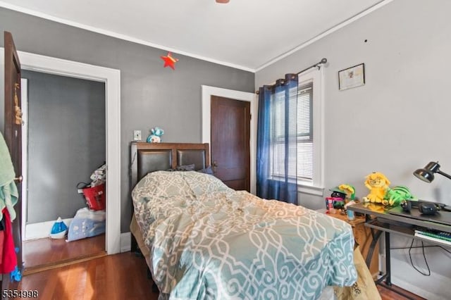 bedroom with ornamental molding and wood finished floors