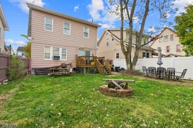 back of property with a lawn, a deck, a fenced backyard, an outdoor fire pit, and stairs