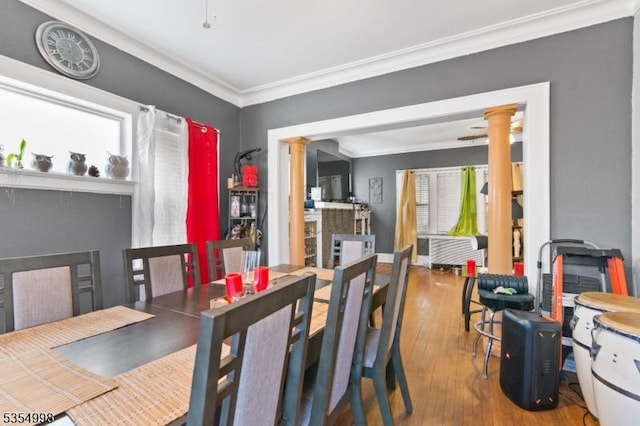 dining area featuring ornate columns, ornamental molding, and hardwood / wood-style floors
