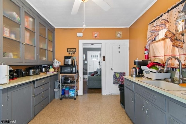 kitchen featuring ceiling fan, crown molding, black microwave, gray cabinetry, and a sink