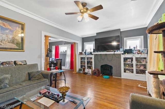 living area featuring crown molding, a ceiling fan, plenty of natural light, and wood finished floors