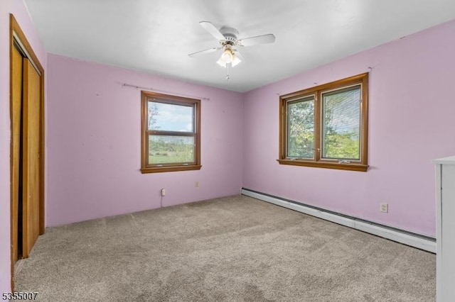 unfurnished bedroom with baseboard heating, carpet, a closet, and ceiling fan