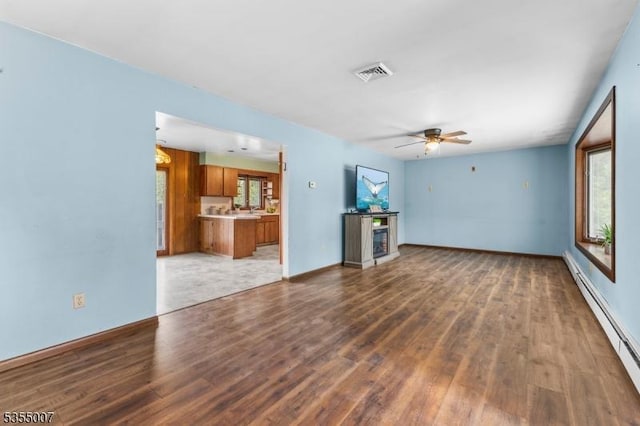 unfurnished living room with baseboard heating, wood finished floors, a ceiling fan, and baseboards
