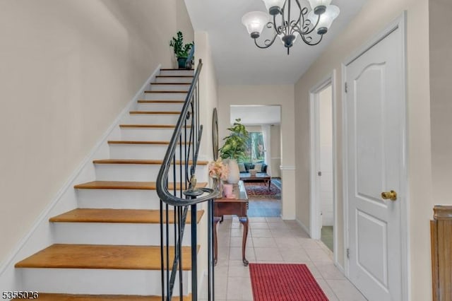 stairway with an inviting chandelier, tile patterned floors, and baseboards