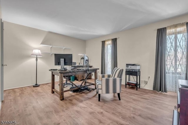 office featuring baseboards, a healthy amount of sunlight, and wood finished floors