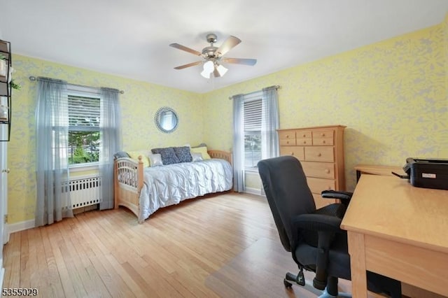 bedroom with baseboards, radiator, hardwood / wood-style floors, and wallpapered walls