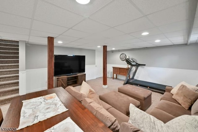 living area with a wainscoted wall, stairs, and a paneled ceiling