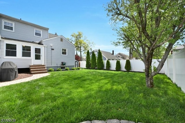 view of yard featuring entry steps and a fenced backyard