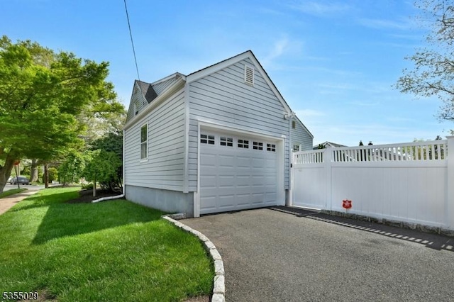 view of side of property with fence, a yard, and aphalt driveway