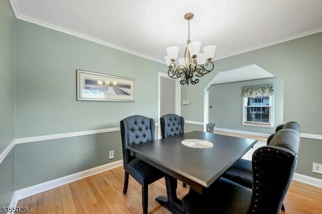 dining room with light wood-type flooring, crown molding, and a chandelier