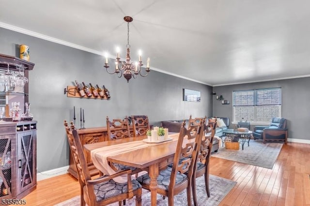 dining room featuring crown molding, a chandelier, and light wood-type flooring