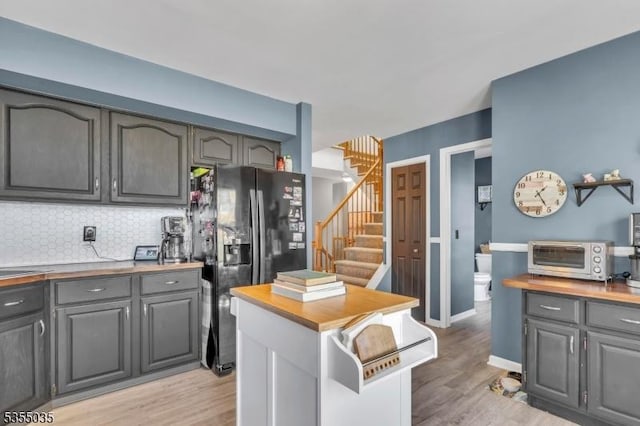 kitchen featuring a toaster, gray cabinets, a kitchen island, and black refrigerator with ice dispenser
