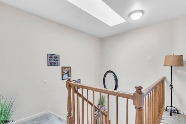 hall featuring carpet floors, a skylight, an upstairs landing, and baseboards
