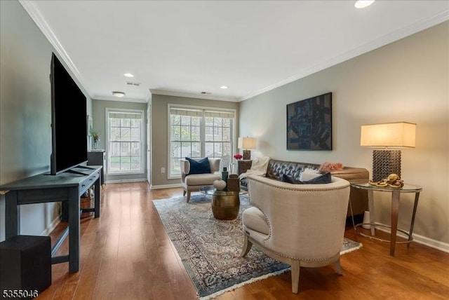 living area featuring crown molding, baseboards, wood finished floors, and visible vents