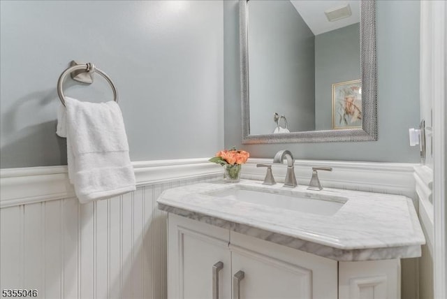 bathroom with vanity, visible vents, and a wainscoted wall