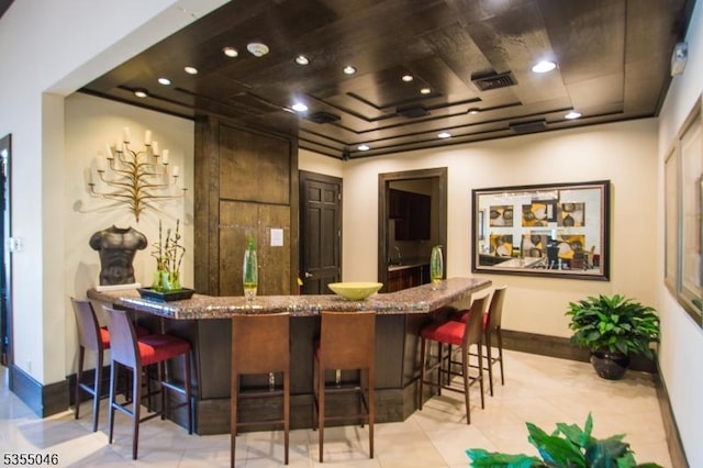 bar with light tile patterned floors, baseboards, wet bar, and visible vents