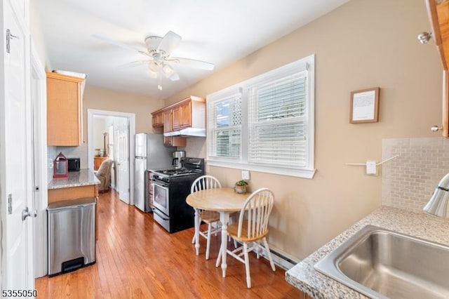kitchen with stainless steel range with gas stovetop, a sink, under cabinet range hood, and tasteful backsplash
