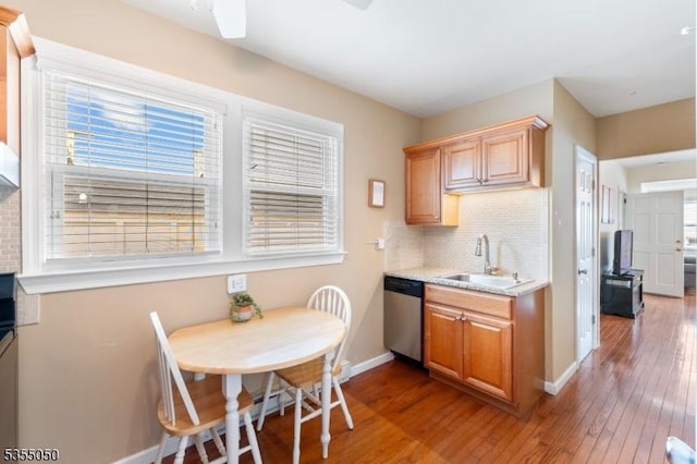 kitchen featuring a sink, baseboards, dishwasher, hardwood / wood-style floors, and light countertops