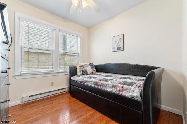bedroom featuring a baseboard radiator, wood-type flooring, baseboards, and ceiling fan
