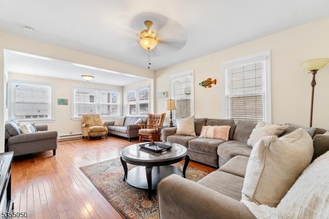 living room with light wood-style floors, ceiling fan, and a baseboard heating unit