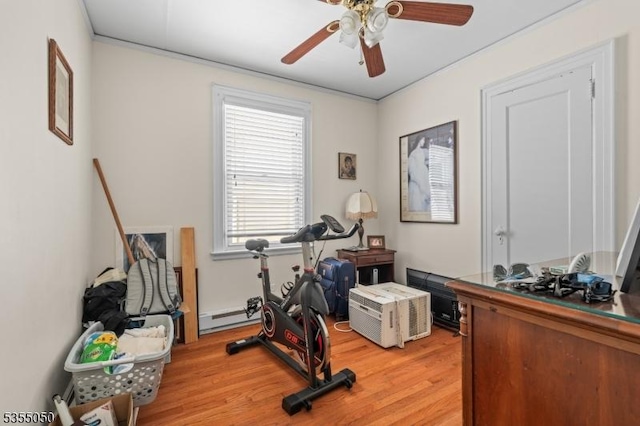 workout area with light wood-style flooring, a baseboard radiator, ceiling fan, and ornamental molding