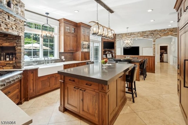 kitchen featuring a chandelier, brown cabinets, a kitchen island, glass insert cabinets, and recessed lighting