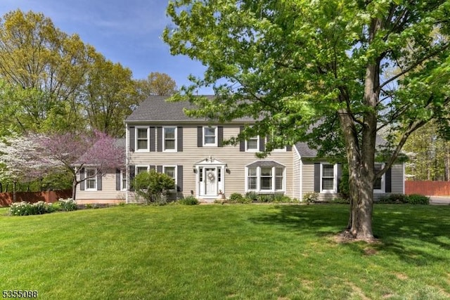 colonial home featuring fence and a front yard