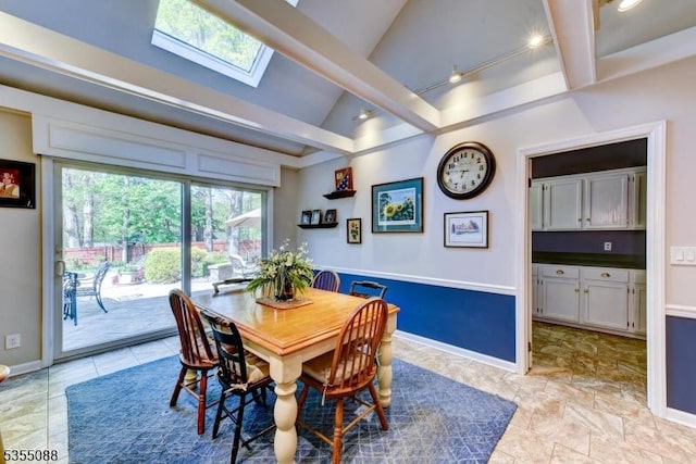 dining area with baseboards and vaulted ceiling with skylight
