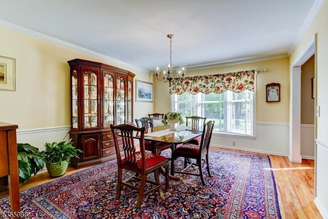 dining area featuring crown molding, a chandelier, and light wood finished floors