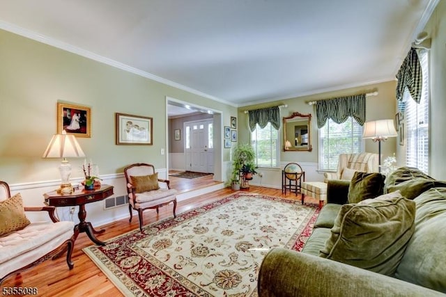 living room with visible vents, ornamental molding, and wood finished floors