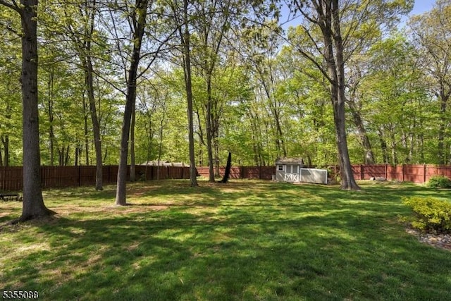 view of yard featuring an outbuilding, a fenced backyard, and a shed