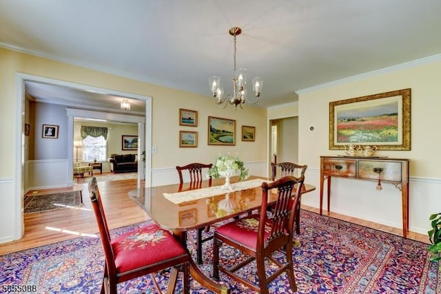 dining area featuring an inviting chandelier, ornamental molding, and wood finished floors