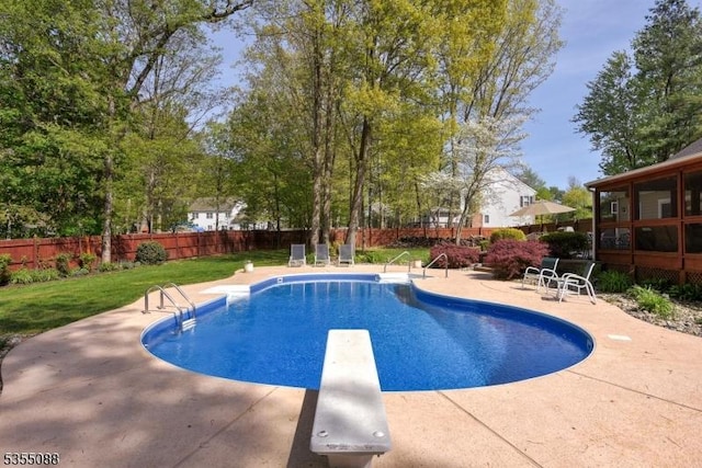 view of swimming pool with a lawn, a diving board, fence, and a patio