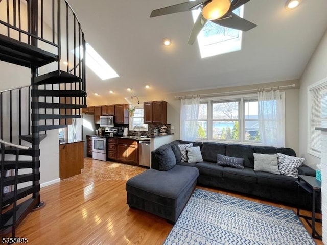 living area with ceiling fan, stairway, light wood-type flooring, recessed lighting, and a skylight
