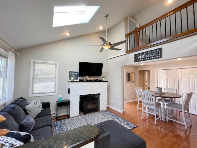 living room featuring ceiling fan, a skylight, wood finished floors, high vaulted ceiling, and recessed lighting