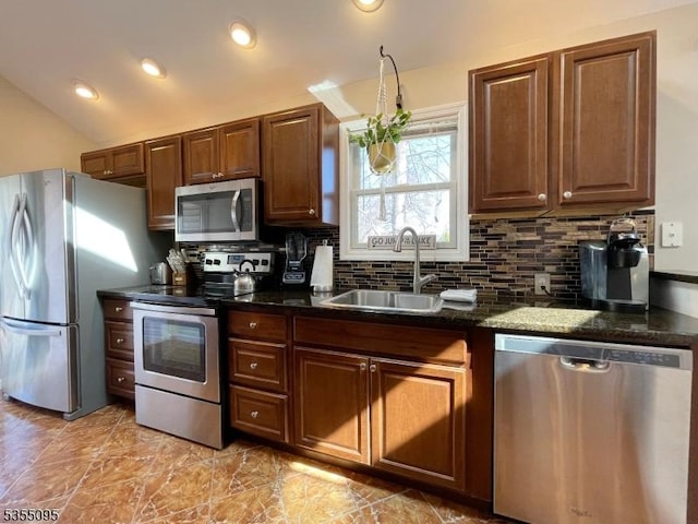 kitchen with a sink, appliances with stainless steel finishes, backsplash, and vaulted ceiling