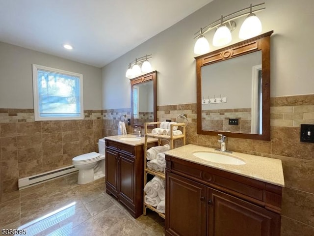 bathroom featuring a sink, tile walls, wainscoting, and a baseboard heating unit