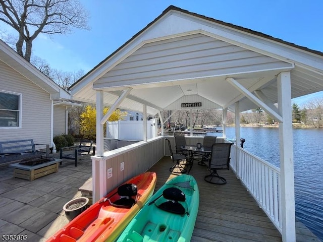 view of dock with a water view, a gazebo, and outdoor dining space