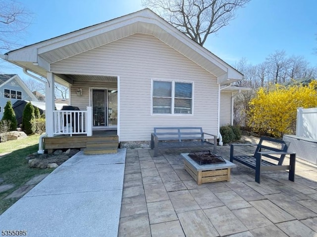 back of property with a porch, a fire pit, and a patio area