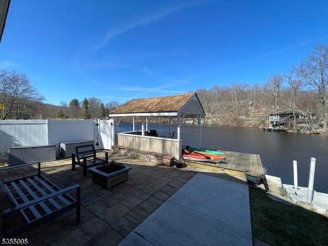 view of patio with a gazebo, a water view, fence, and a dock