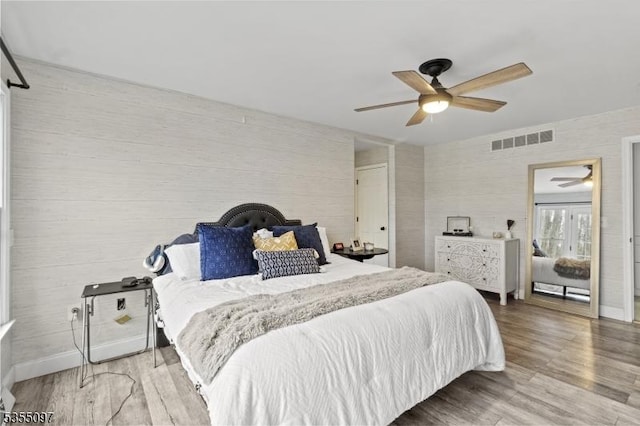 bedroom with visible vents, a ceiling fan, baseboards, and wood finished floors