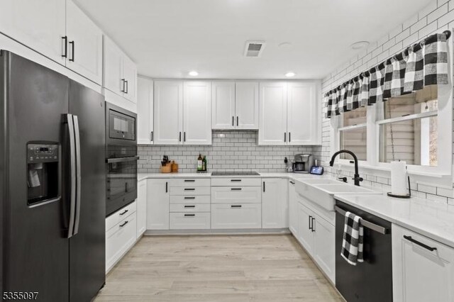 kitchen featuring visible vents, a sink, black appliances, and tasteful backsplash